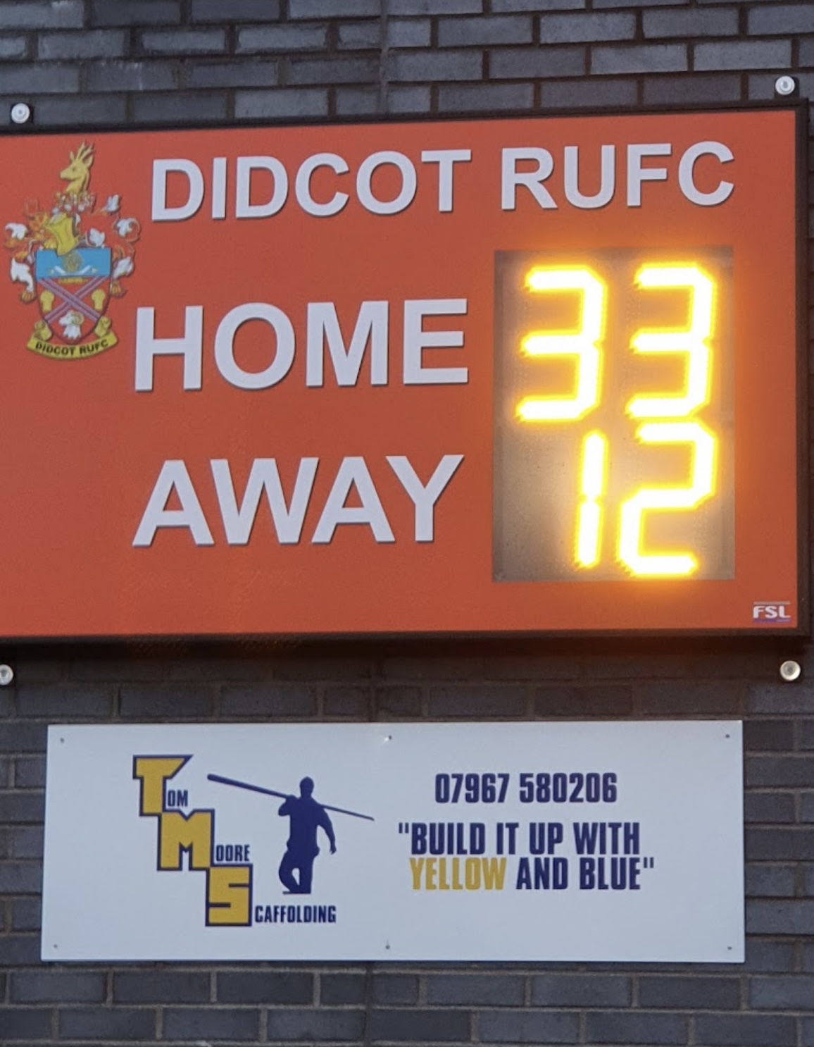 Tom Moore Scaffolding sponsor board at Didcot RUFC beneath the scoreboard