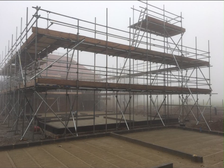 Independent scaffold with boarded lifts on a new-build plot in early morning mist